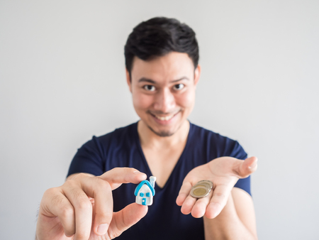 Asian man showing small house and coin. Concept of buing house and finance.の写真素材