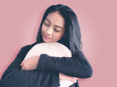Asian woman hugging a cusion to keep warm and missing her lover.の写真素材