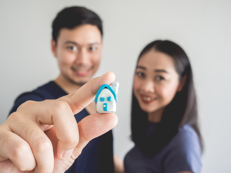 Happy couple lover showing small house in hand. Concept of buying house to start a family.の写真素材