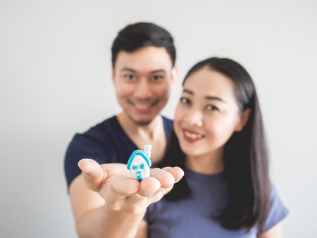 Happy couple lover showing small house in hand. Concept of buying house to start a family.の写真素材