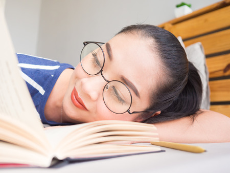 Asian woman lie down on bed and reading book.の写真素材