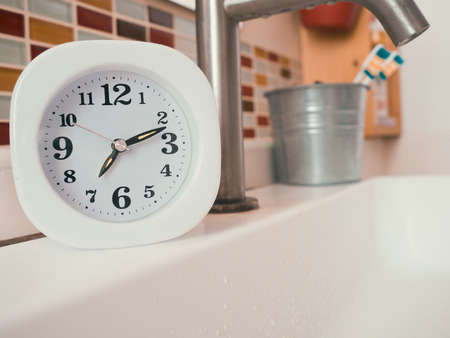 Simple white clock in the bathroom. Concept of life routine.
