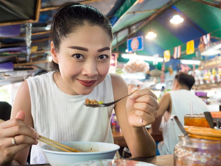 Asian woman eating noodle in Thai local restaurant in Thailand.の写真素材