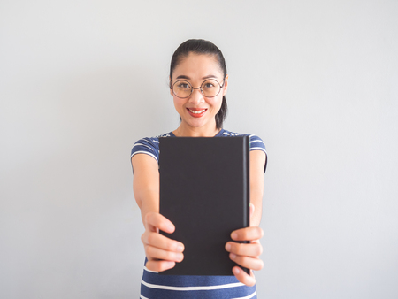 Nerdy Asian woman smiles and holding a good book.の写真素材