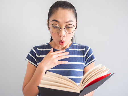 Nerdy Asian woman got a surprised idea from the book.の写真素材