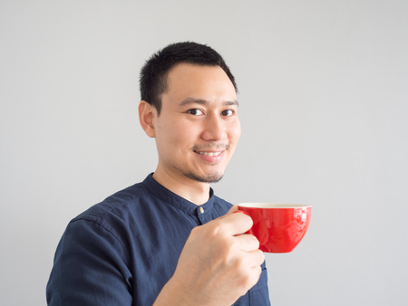 Asian man take a sip of coffee in red cup.の写真素材