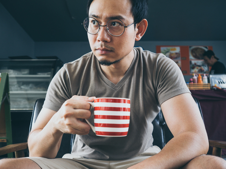 Asian man drinking hot coffee cocoa or tea on wooden table.の写真素材