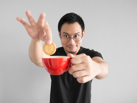 Funny Asian man showing how to eat cookies in a happy way.の写真素材