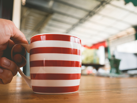 Red and white stripe mug of hot tea on wooden table.の写真素材