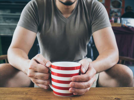 Asian man drinking hot coffee cocoa or tea on wooden table.の写真素材