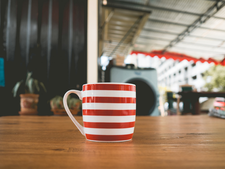 Red and white stripe mug of hot tea on wooden table.の写真素材