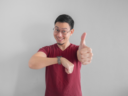 Happy and surprised Asian man who is looking at his watch.