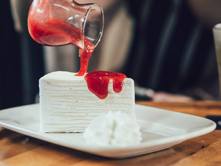 Close up of crepe cake with strawberry sauce.