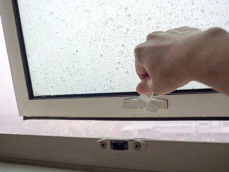 Hand reach to open the window to see the rain.