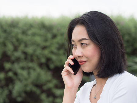 Asian woman has a good happy mobile phone conversation.の写真素材