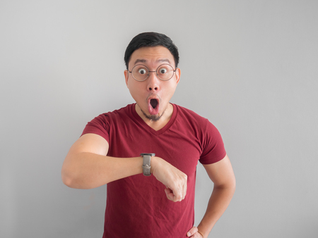 Happy and surprised Asian man who is looking at his watch.の写真素材