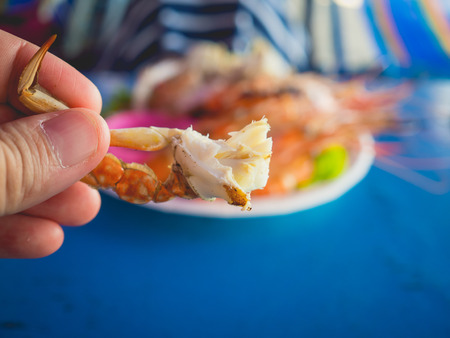 Close up of Asian woman eating local grilled seafood of Thailand beach.の写真素材
