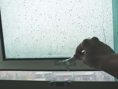 Hand reach to open the window to see the rain.