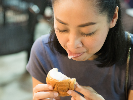 Asian woman eating Stuffed creamy buns.の写真素材