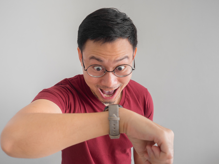 Happy and surprised Asian man who is looking at his watch.の写真素材