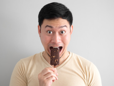 Funny face Asian man eat chocolate vanilla ice pop.の写真素材