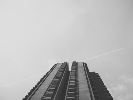 Black and white image of high condominium building from ground angle.