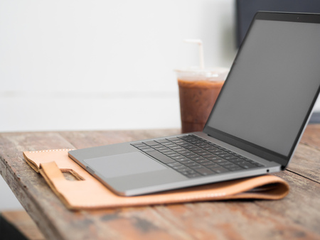 Laptop on wooden desk with iced coffee in the cafe.