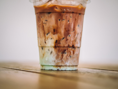 Plastic cup of iced cocoa milk with green mint aroma.