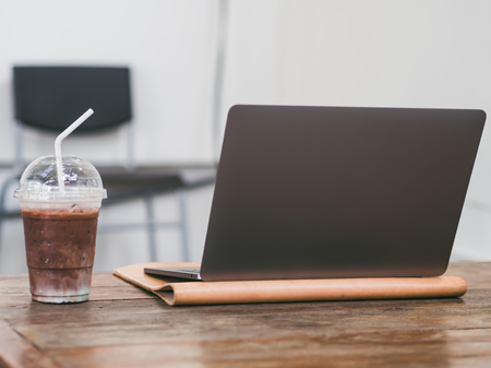 Laptop and iced coffee in the cafe. Concept of freelance working and relax.の写真素材