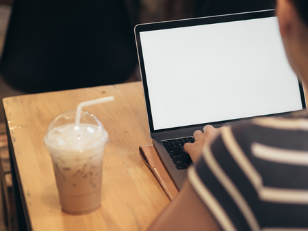 Aisan woman is using laptop with a plassic cup of iced coffee.の写真素材