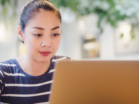 Asian woman working on her laptop in the cafe under tunsten light.の写真素材