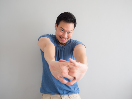 Asian man in blue t-shirt is stretching his arms.の写真素材