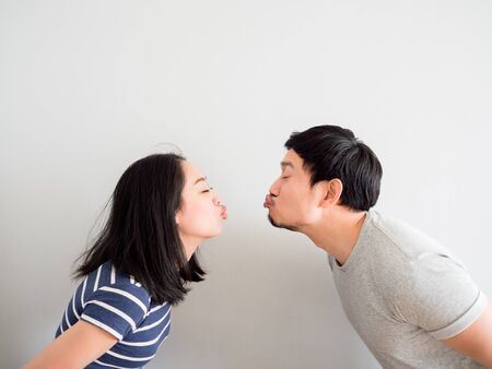 Funny lovely Asian couple trying to kiss each other. Concept of comedy love.の写真素材