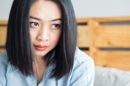 Asian woman sits on her bed in  day time.の写真素材