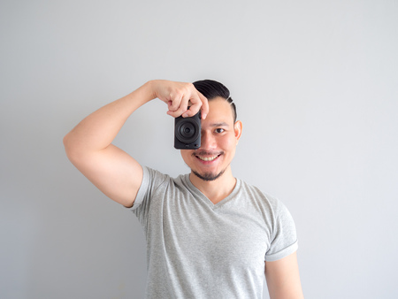 Asian man is holding a mirrorless camera and try to take a photo.のeditorial素材
