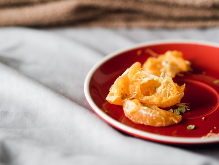 Some left over of orange in red dish on bed on good relax day.
