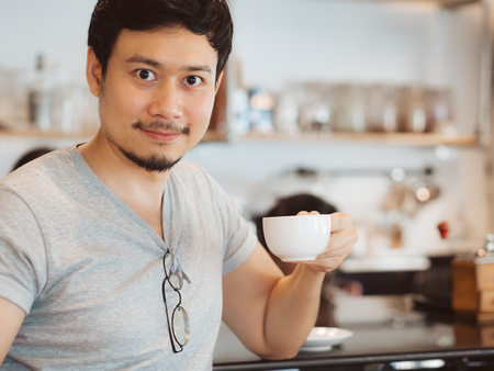 Asian man is drinking hot coffee in the coffee cafe.の写真素材