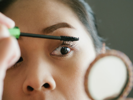 Asian woman is putting make up mascara on her eyelashes.の写真素材