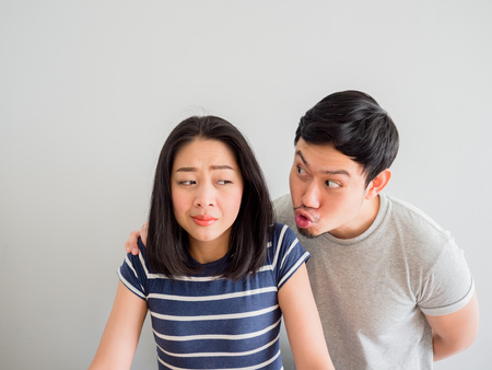 Funny lovely Asian couple trying to kiss each other. Concept of comedy love.の写真素材