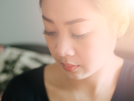 Close up face of Asian woman in normal emotion with low light from window.