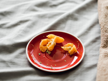 Some left over of orange in red dish on bed on good relax day.の写真素材