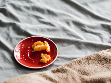 Some left over of orange in red dish on bed on good relax day.の写真素材