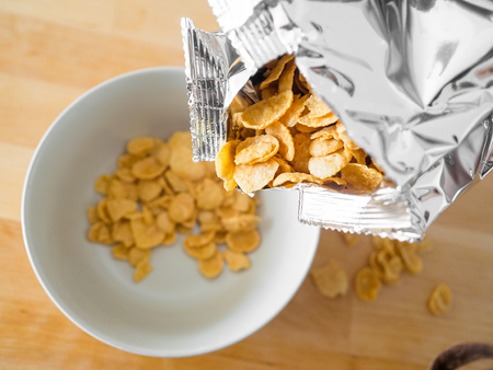 Cornflakes cereal breakfast on wooden table.