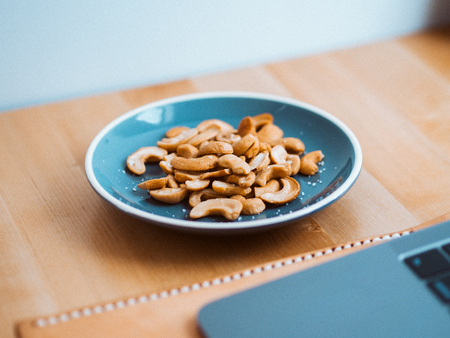 Some cashew nuts on small snack blue dish on work desk.の写真素材