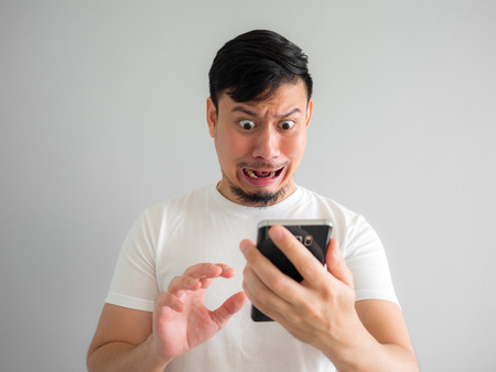 Shocked and scary face of Asian man get yelled from smartphone.  See something scary in smartphone.の写真素材