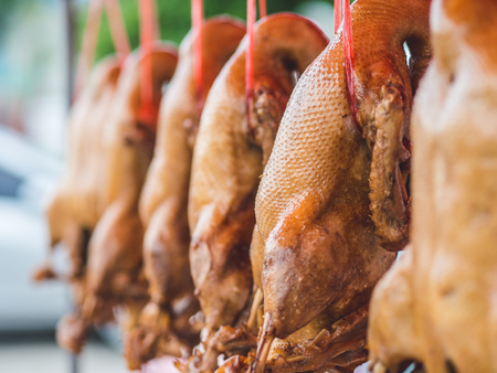Thai steamed ducks are hanging on the wire of Thai local market carts.の写真素材