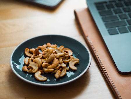 Some cashew nuts on small snack blue dish on work desk.の写真素材