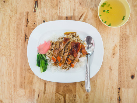 Rice with roasted duck in white plastic dish served on wooden table.の写真素材