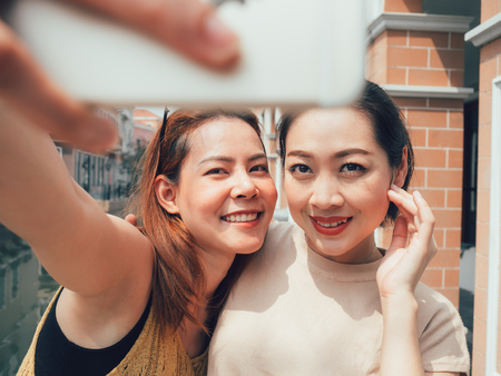 Two friends of Asian tourist girls are taking selfie with the city view.の写真素材