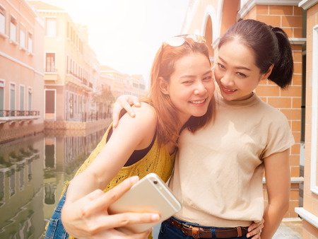 Two friends of Asian tourist girls are taking selfie with the city view.の写真素材